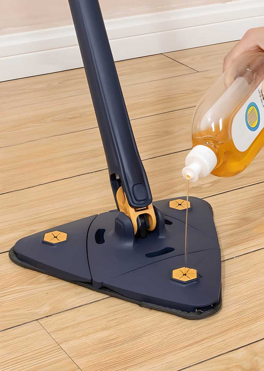 Adjustable triangle mop for tight spaces with a bottle dispensing cleaning solution on a wooden floor