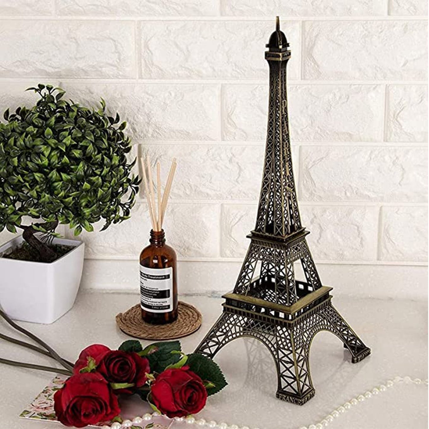 Antique Eiffel Tower statue on a table with roses and decorative plant for home improvement decor