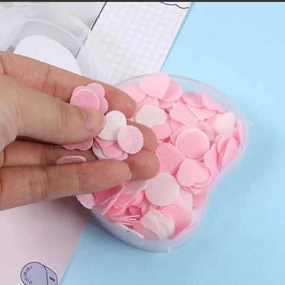 Hand holding apple scented paper soap in a container filled with colorful soap sheets