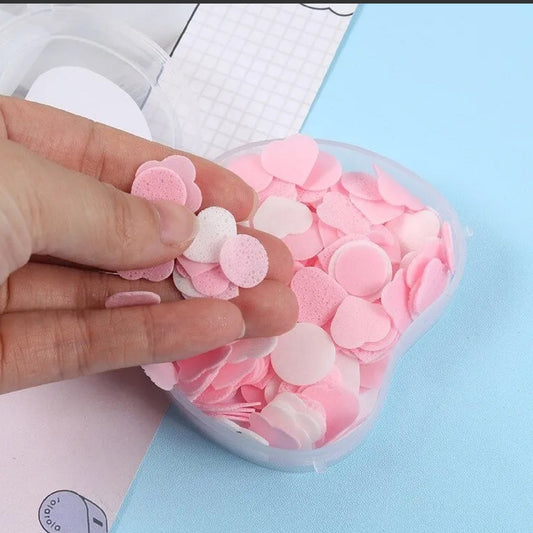 Hand holding apple scented paper soap in a container filled with colorful soap sheets
