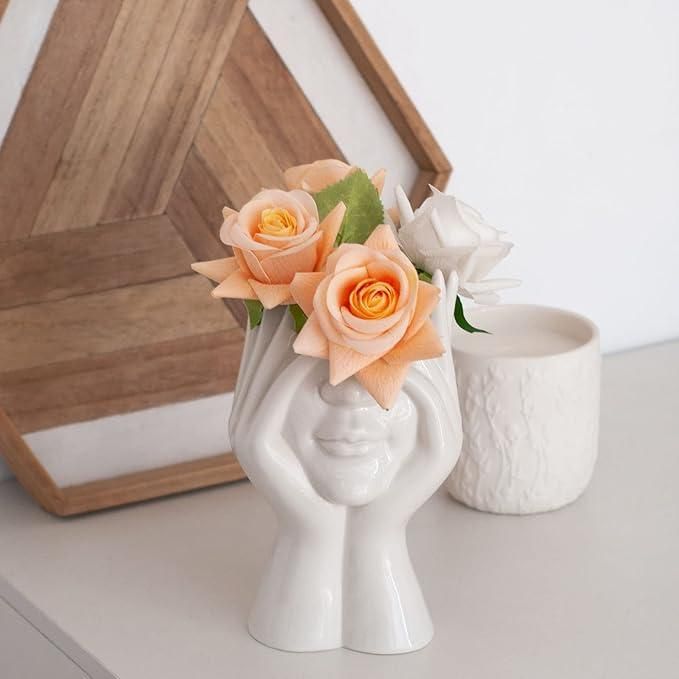 Artistic hand face vase for home decor filled with peach and white roses and greenery