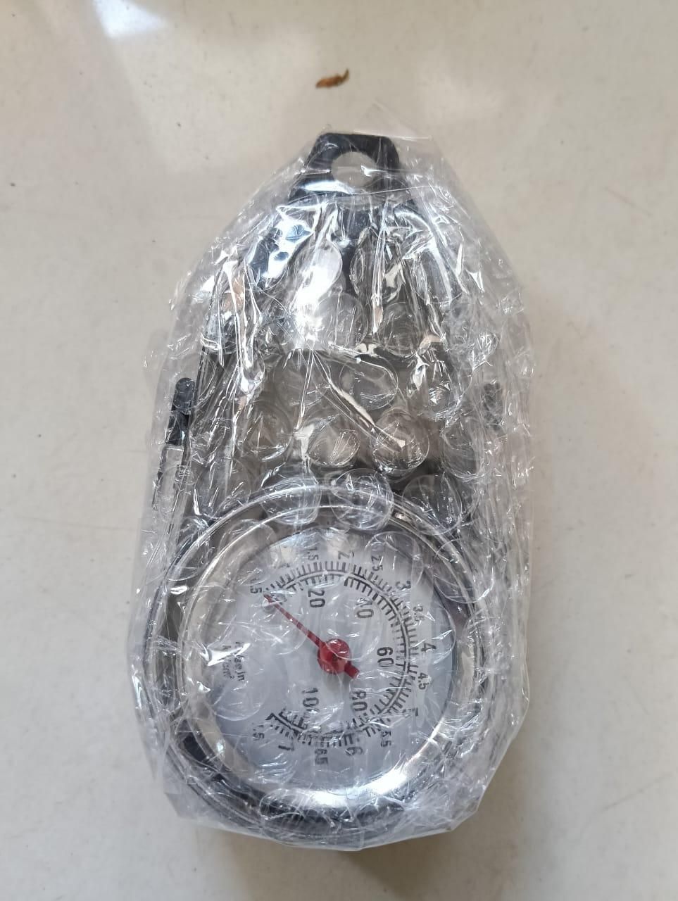 Auto tire pressure gauge wrapped in plastic with a clear dial and red indicator for accurate readings