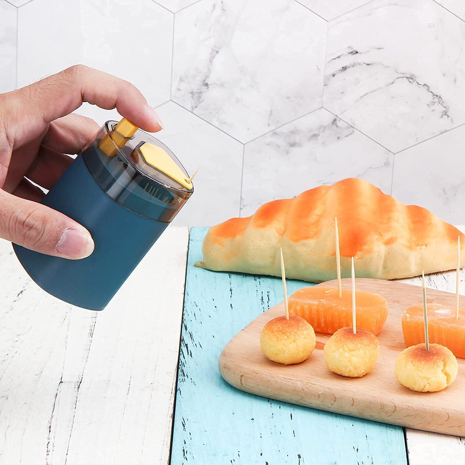 Your Brand automatic toothpick dispenser in use with appetizers arranged on a cutting board