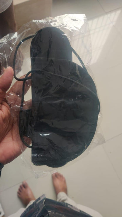 Black travel eye mask with elastic band in plastic packaging not an adjustable luggage strap