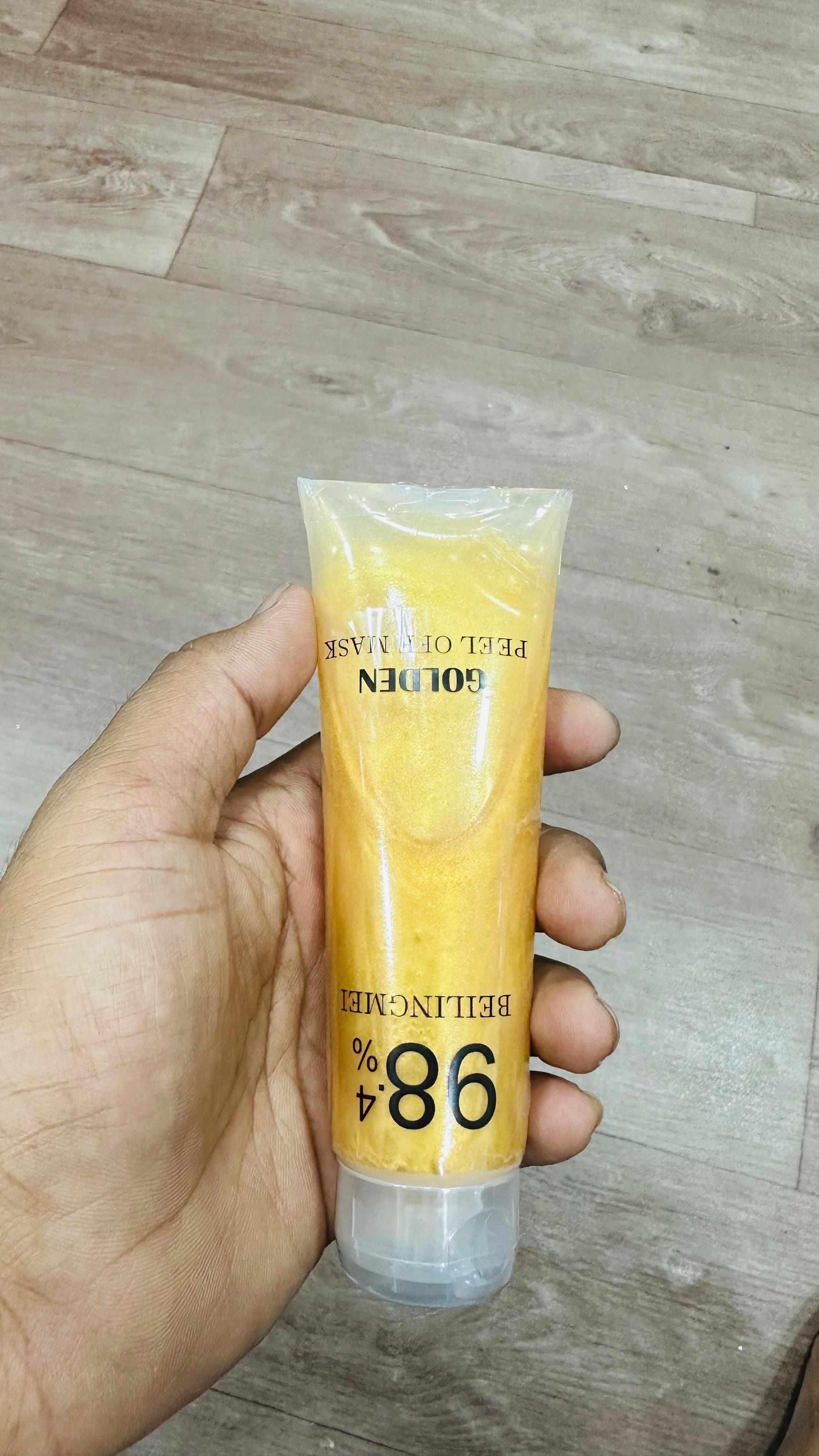 Gold face mask for glowing skin in a clear tube showing a shimmering golden peel-off formula