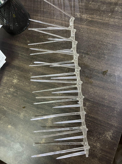 Transparent plastic bird spikes for balcony placed on a wooden surface to prevent birds from landing