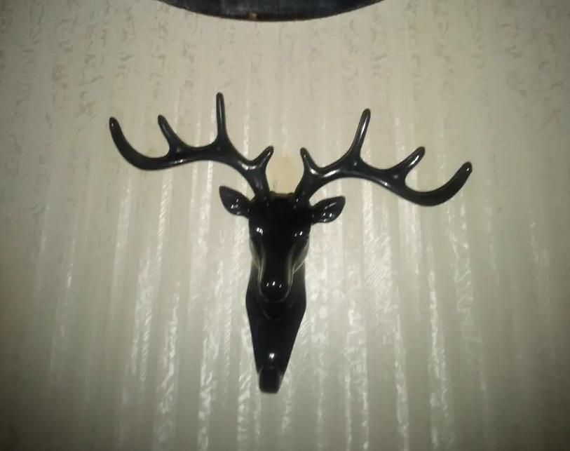 Black deer head self adhesive coat hook mounted on textured wall for hanging items