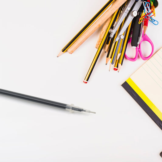 Black pen refill with assorted office supplies including pencils, clips, and notepad