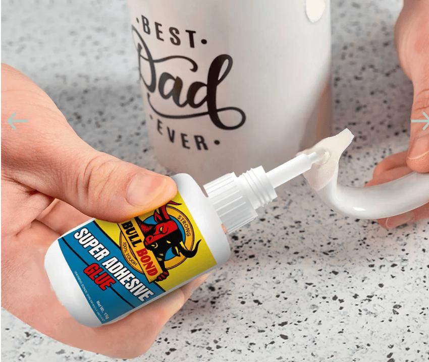 Person applying strong bonding glue for home use from small bottle to repair broken mug handle on countertop