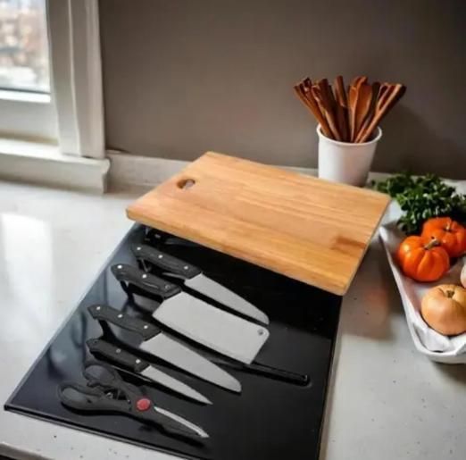 wooden chopping board with knife set on black magnetic tray on kitchen counter with tomatoes and utensils