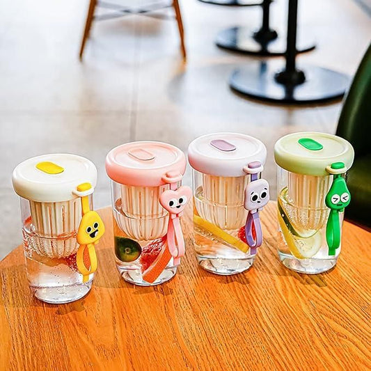 Colorful glass smoothie tumbler with lid and cute character keychains on wooden table