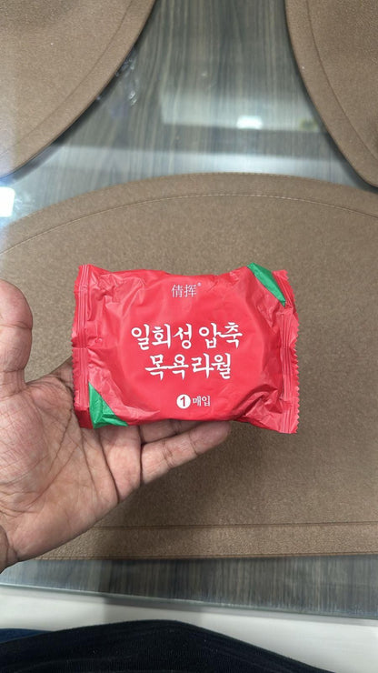 Compressed bath towel tablets in red packaging, ideal for travel and convenience
