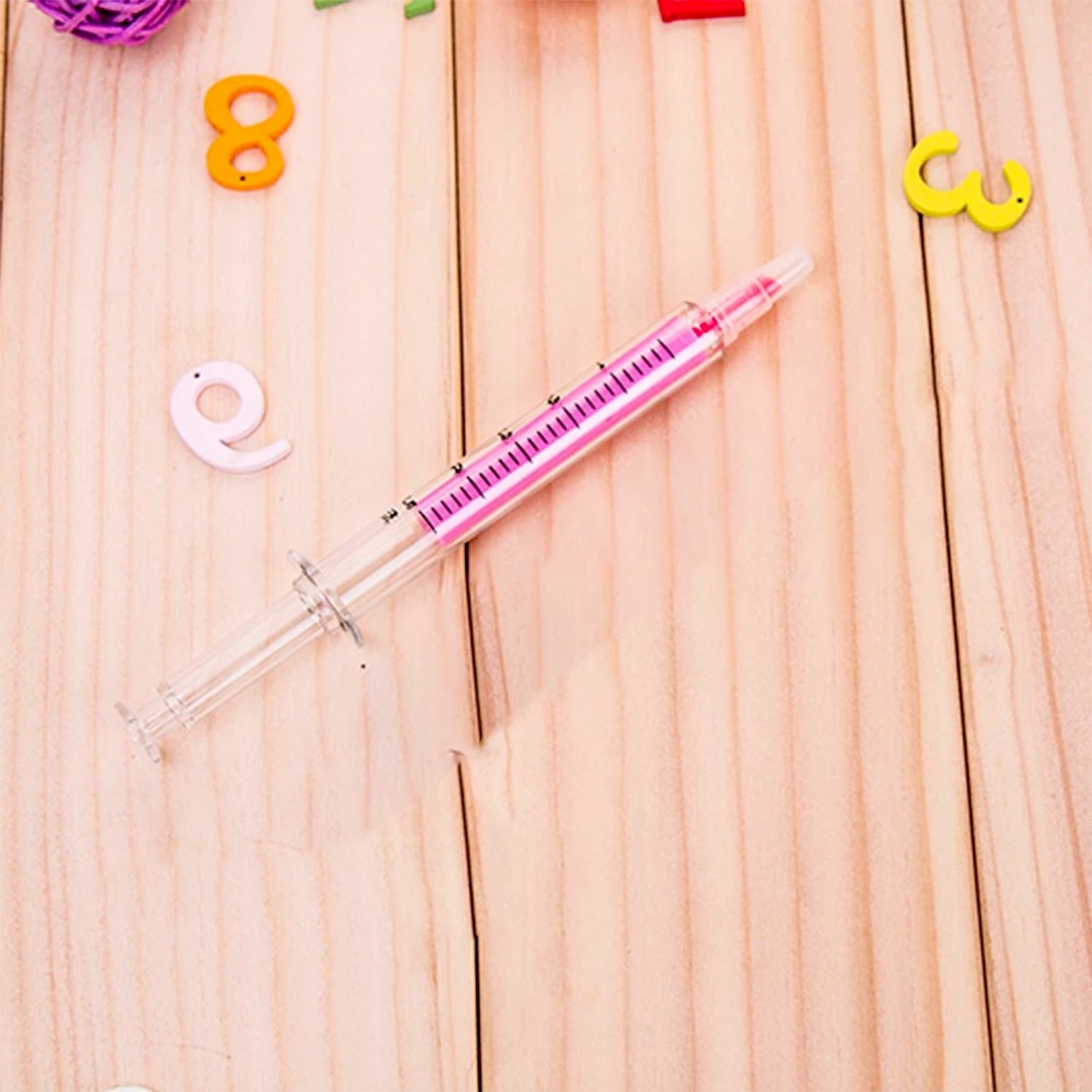 Creative fluorescent highlighter pen in pink surrounded by colorful educational letters on a wooden surface