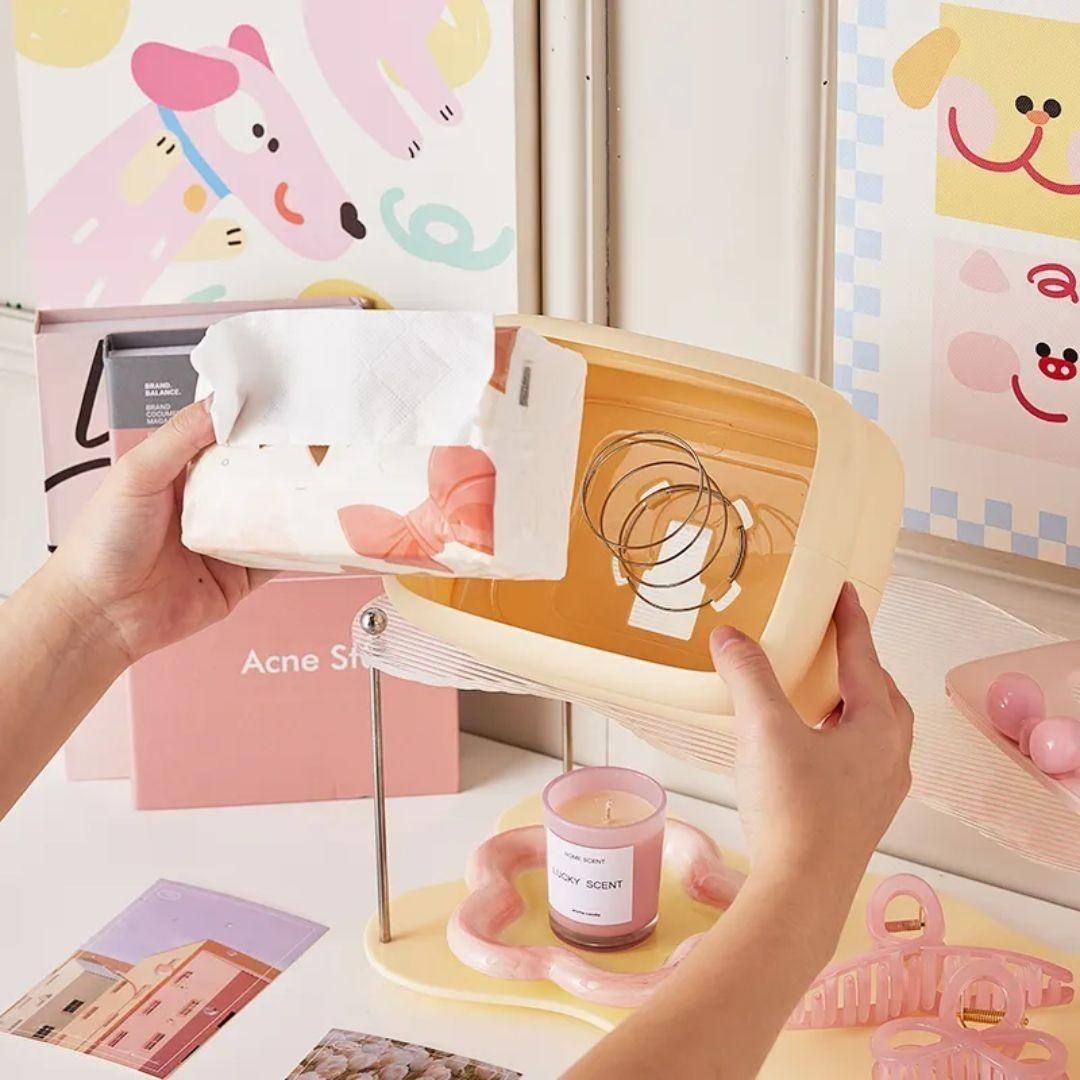 Hands holding a creative square tissue box holder with a stylish design and colorful accessories