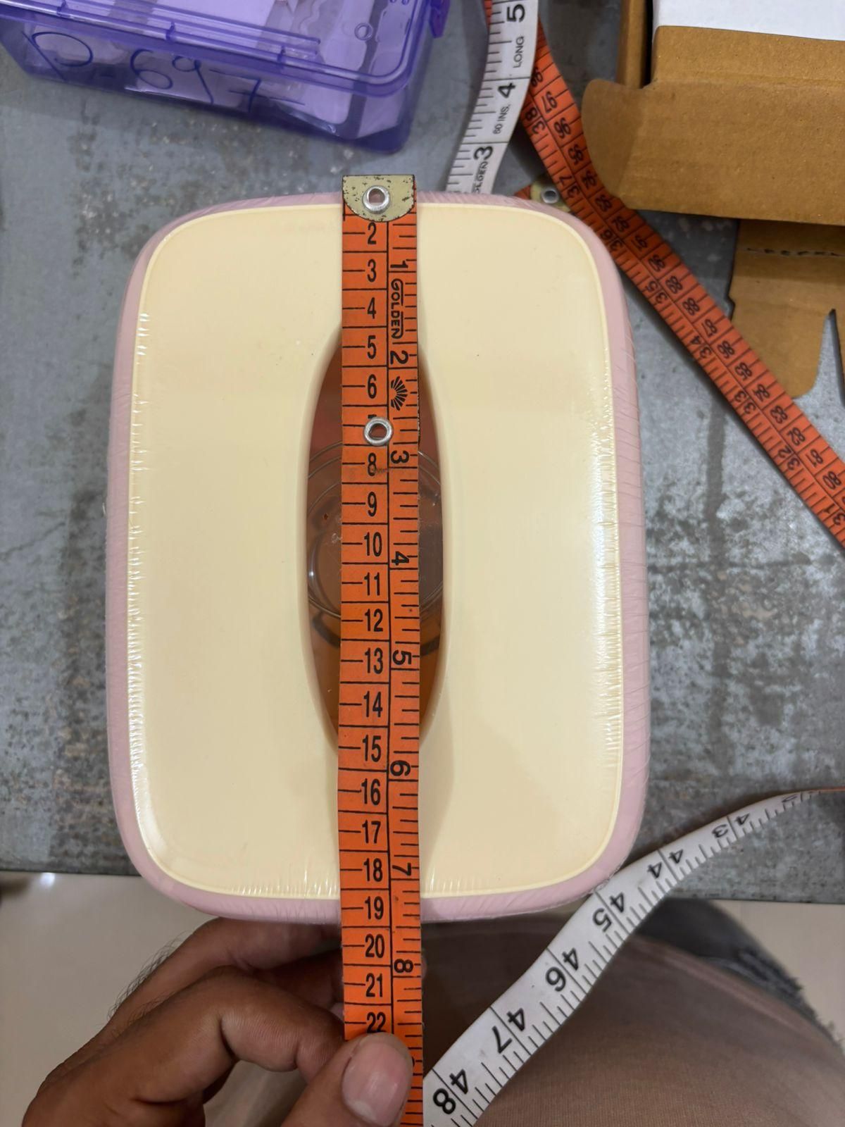 Creative square tissue box holder with a measuring tape for size reference on a gray surface