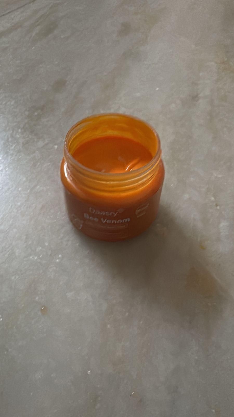 Open jar of bee venom skin cream with orange contents for skincare enthusiasts