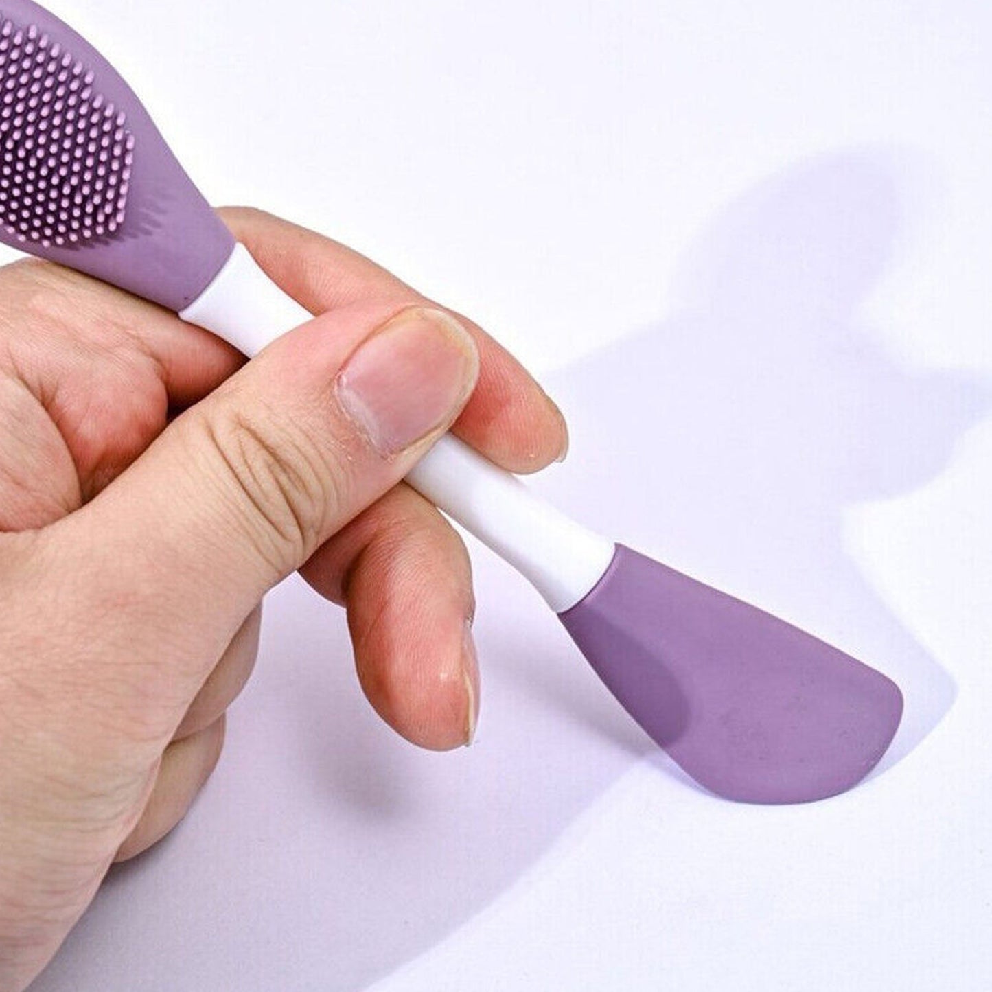 Double-headed silicone mask brush in hand, ideal for applying skincare masks evenly