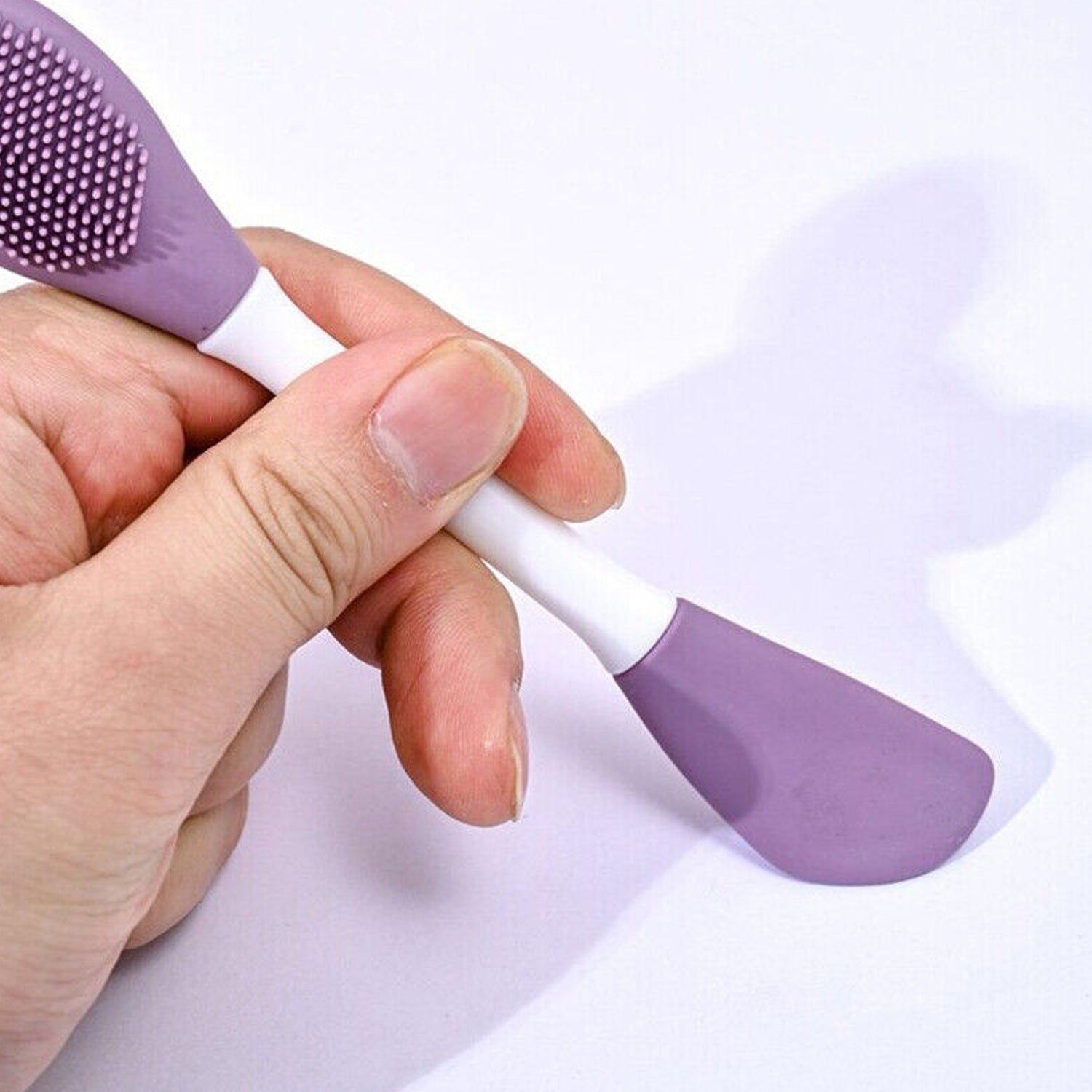 Double-headed silicone mask brush in hand, ideal for applying skincare masks evenly