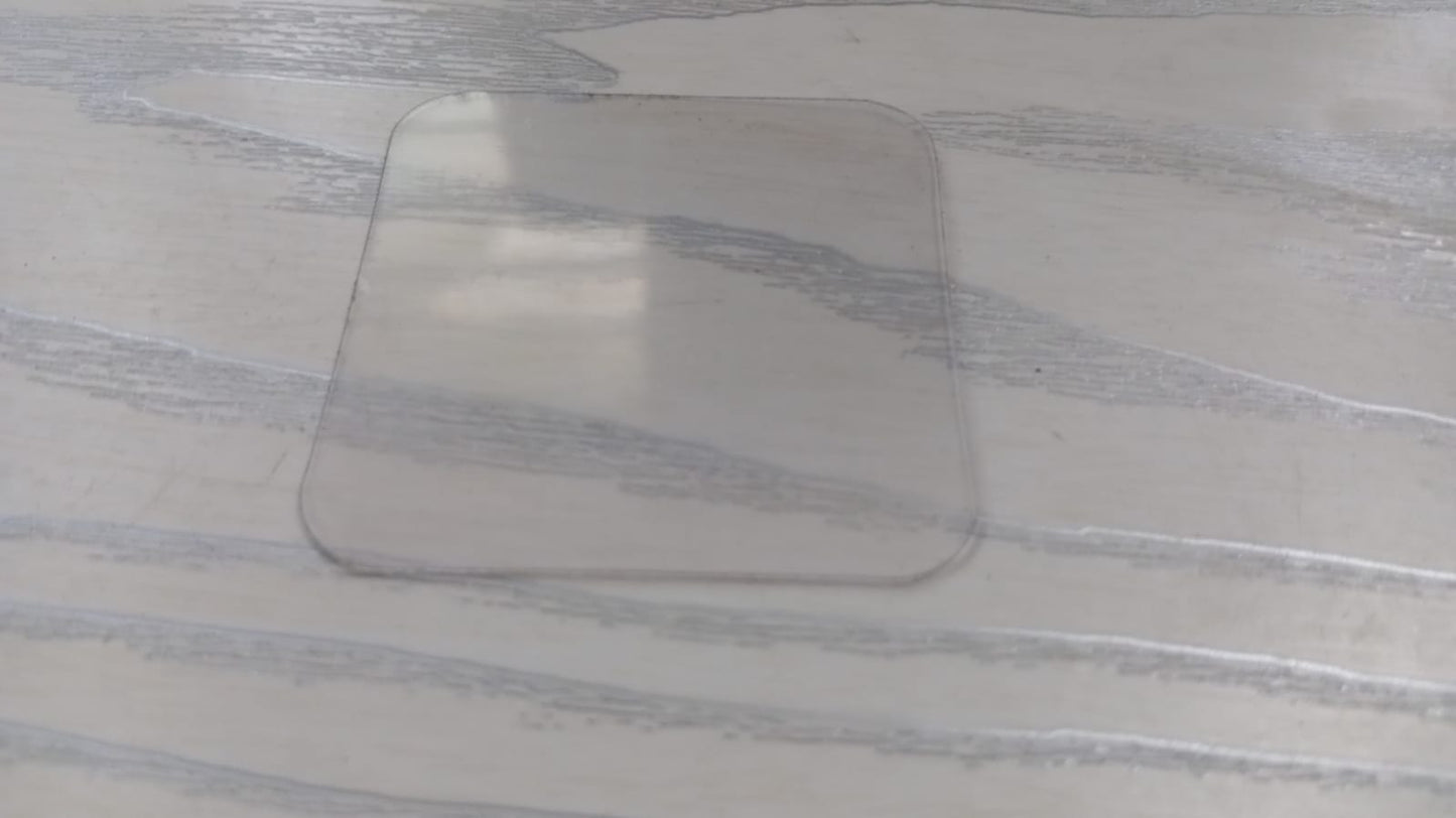Clear square piece of double-sided nano adhesive tape on a wooden surface for versatile bonding solutions