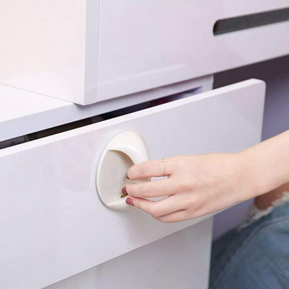 White circular adhesive handles for cabinets on a glossy white drawer being pulled by a hand
