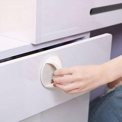 White circular adhesive handles for cabinets on a glossy white drawer being pulled by a hand