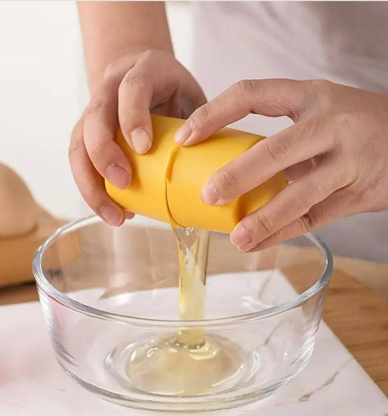 Hands using a yellow egg topper cutter tool to separate egg yolk into a glass bowl