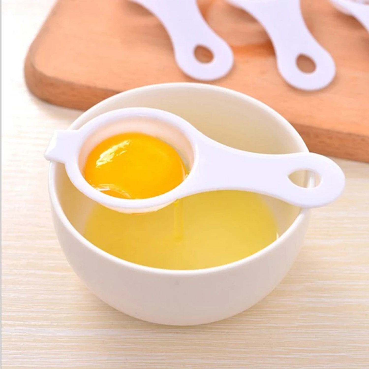 White egg yolk separator resting on a bowl with a separated egg yolk for easy cooking