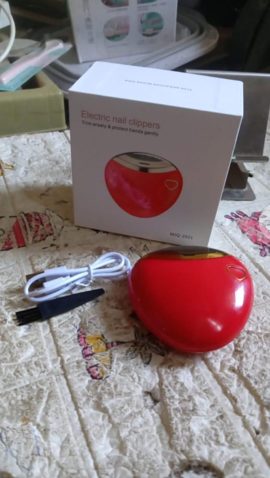 Red electric nail clipper with packaging and charging cable for easy nail care at home