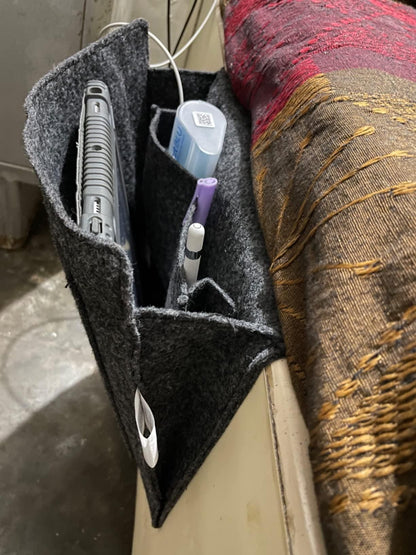 The Gir Farmer felt bedside pocket for essentials holding a remote, pens, and other small items next to a bed
