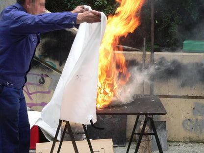 Person using a fire safety blanket for home to extinguish flames on a burning table outdoors