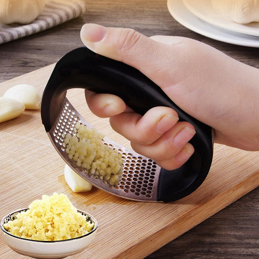 Hand-held garlic ginger crusher for cooking with finely minced garlic on a cutting board