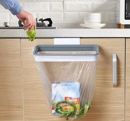 Attachable kitchen garbage bag holder hanging on cabinet door with kitchen waste inside