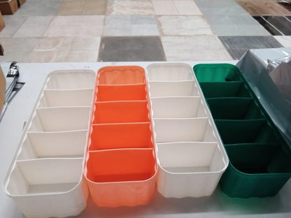 Set of colorful drawer organizers for makeup including white, orange, and green compartments on table