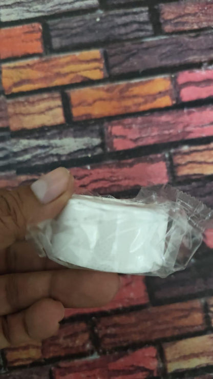 Hand holding a roll of white sweat absorbent adhesive tape wrapped in clear plastic