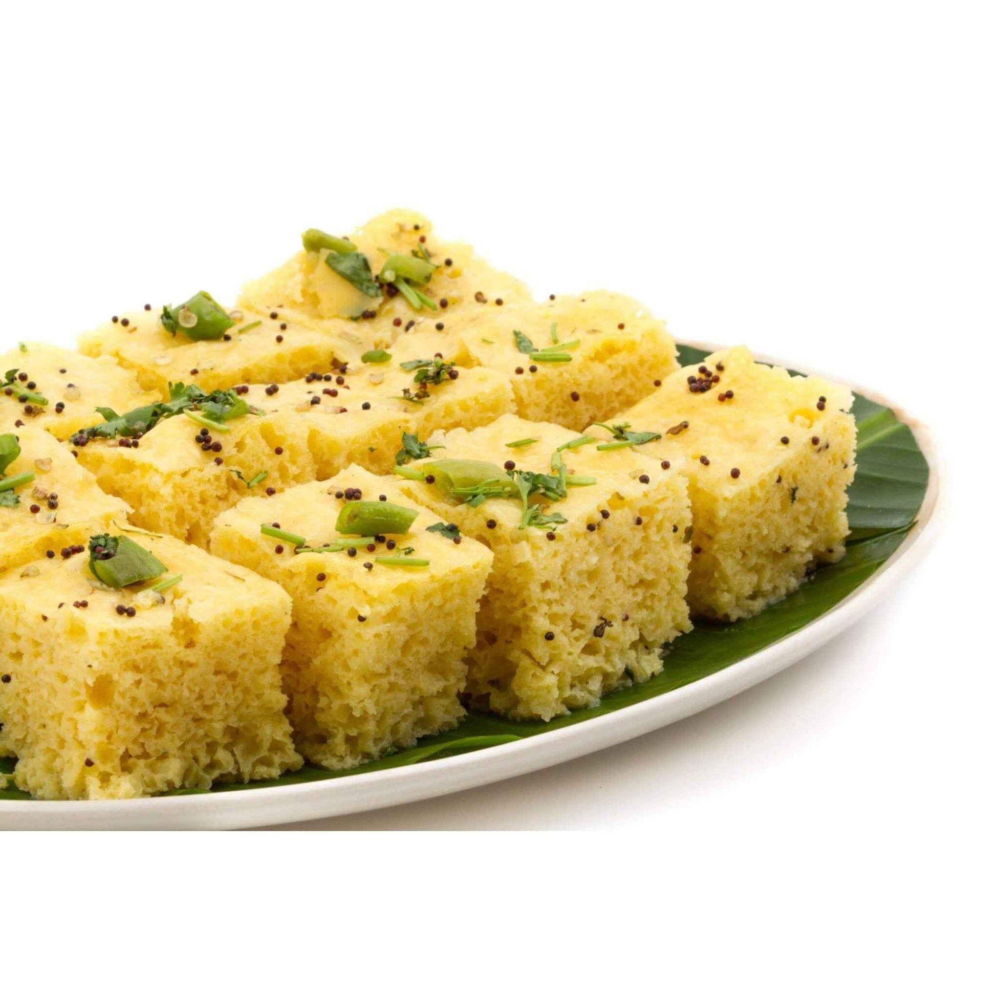 Delicious steamed squares of dhokla made with authentic Gujarati dhokla flour, garnished with green chilies and mustard seeds