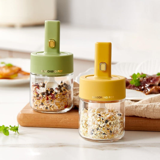 THE GIR FARMER glass seasoning jar with spoon lid in green and yellow filled with spices on kitchen counter