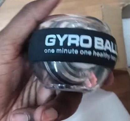 Gyro wrist strengthener ball held in hand, featuring a black band with 'GYRO BALL' text for grip training