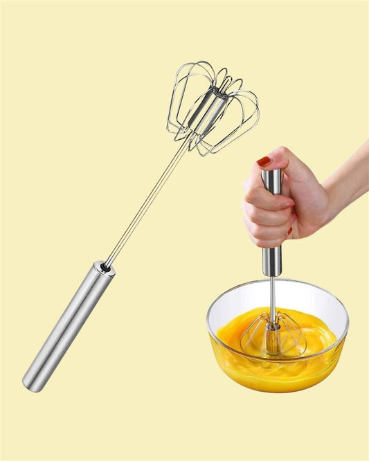 Stainless steel hand whisk mixer for baking held in hand and beating egg mixture in glass bowl