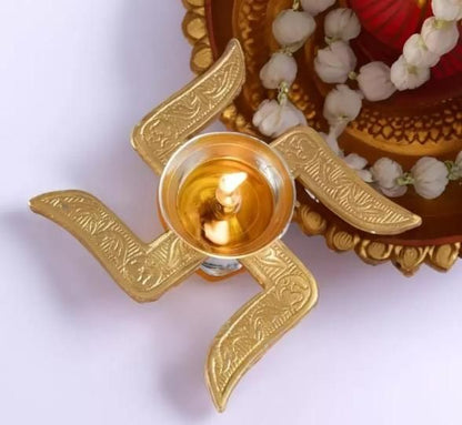 Top view of handcrafted puja brass diya with intricate design and burning wick for traditional worship