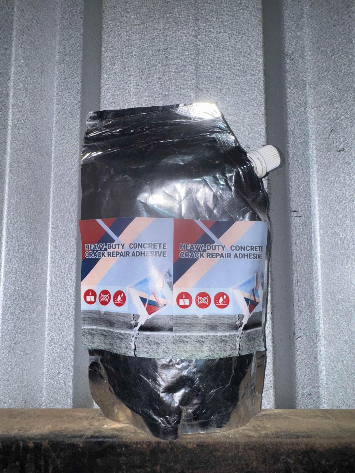 Heavy-duty concrete crack repair adhesive in black flexible pouch with white cap