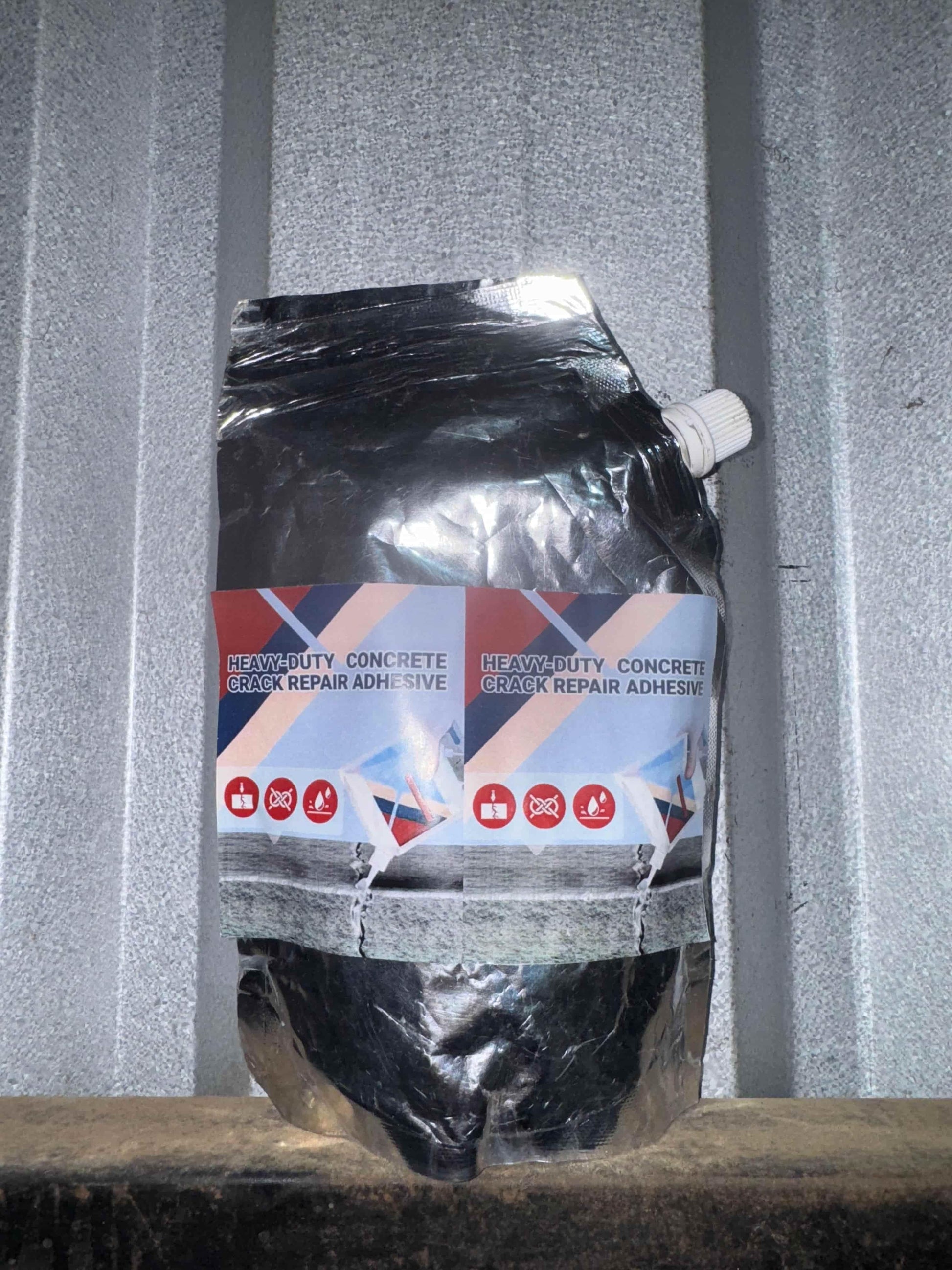 Heavy-duty concrete crack repair adhesive in black flexible pouch with white cap
