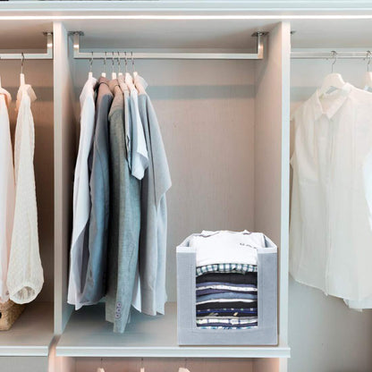 Gray foldable cloth organizer set cube in closet holding neatly folded shirts beside hanging blouses and jackets