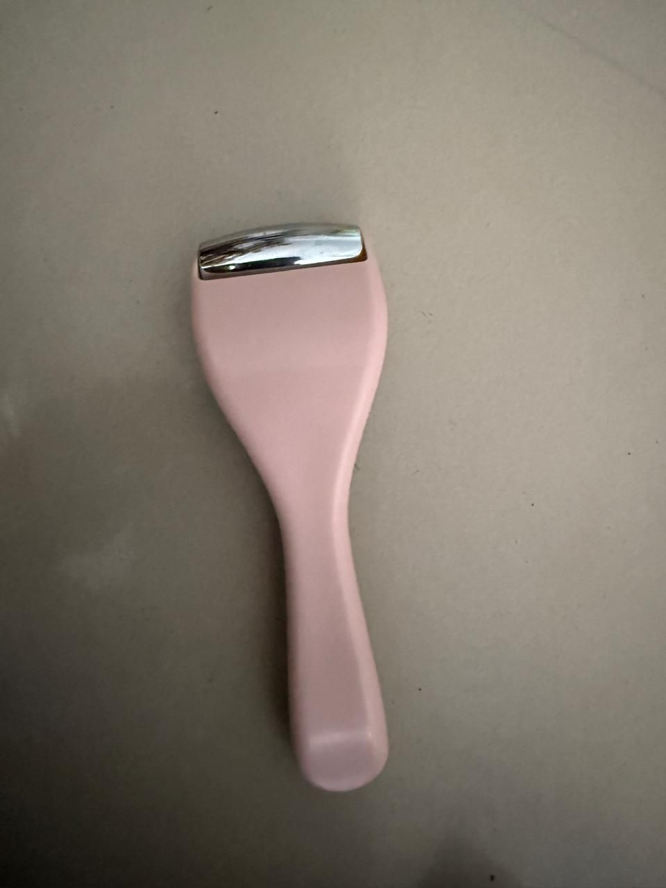Pink ice roller for face with a smooth metal head for reducing puffiness and soothing skin
