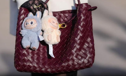 Labubu bunny doll gift plush keychains hanging on a burgundy woven handbag by THE GIR FARMER