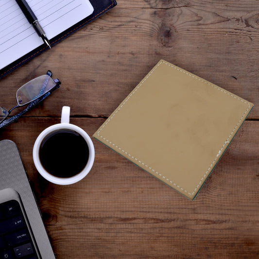Elegant leather tea coaster in tan color placed on a wooden desk with coffee and notepad