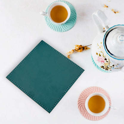 Your Brand leather tea coaster in teal color with tea cups and teapot in the background