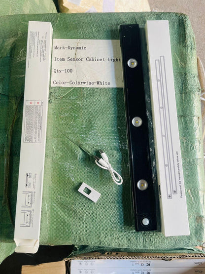 Black LED motion sensor cabinet light with remote and USB charging cable next to white packaging box