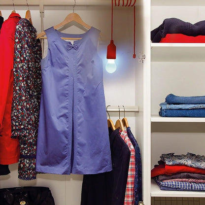 LED pull cord light bulb illuminating a purple dress in a stylish closet