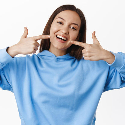 Woman smiling and showing teeth with a six sided soft toothbrush for effective dental care