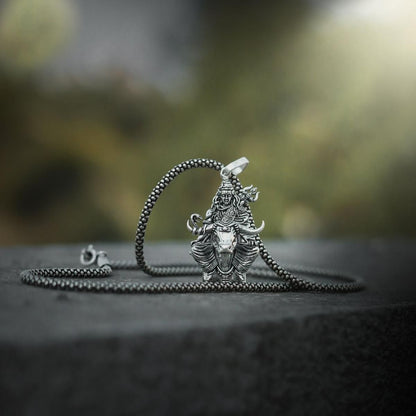 Lord Shiva silver pendant on a chain displayed against a natural background